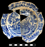 White refined earthenware small plate printed underglaze in medium blue in the Castle and Bridge pattern (Coysh and Henrywood 1982:73). This pattern may represent a view of St. Albans Abbey, Hertfordshire and has been found with the marks of Henshall, Williamson & Co. Henshall & Co. (1790 – 1828), Longport. This vessel is unmarked. 6.50” rim diameter.